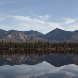 An Alaskan mountain range perfectly mirrored in calm waters.